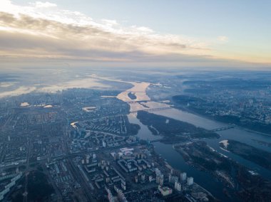 Aerial high flight over Kiev, haze over the city. Autumn morning, the Dnieper River is visible on the horizon. clipart