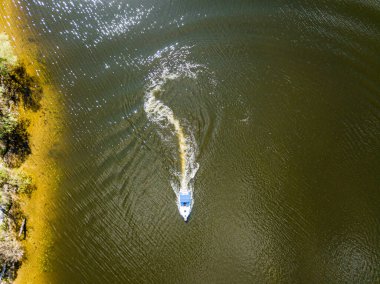 Hava aracı görüntüsü. Güneşli bir günde bir motorlu tekne nehirden geçiyor..