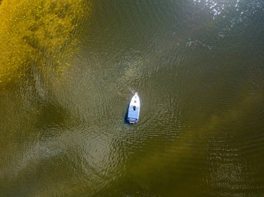 Hava aracı görüntüsü. Güneşli bir günde bir motorlu tekne nehirden geçiyor..