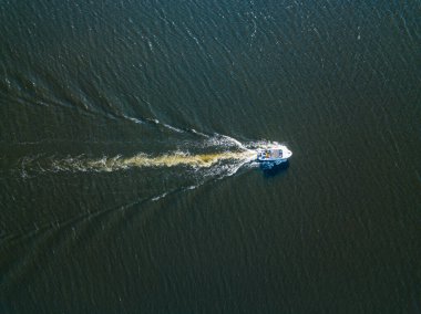 Hava aracı görüntüsü. Motorlu tekne nehir boyunca gidiyor. Güneşli yaz günü, küçük dalgalar.
