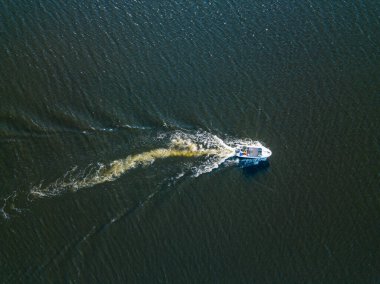 Hava aracı görüntüsü. Motorlu tekne nehir boyunca gidiyor. Güneşli yaz günü, küçük dalgalar.