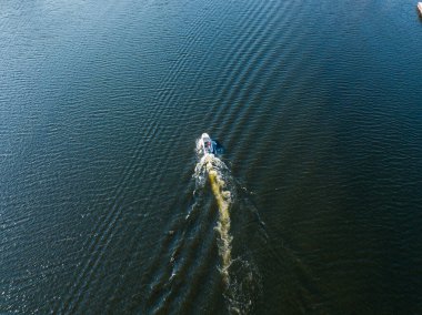 Hava aracı görüntüsü. Motorlu tekne nehir boyunca gidiyor. Güneşli yaz günü, küçük dalgalar.