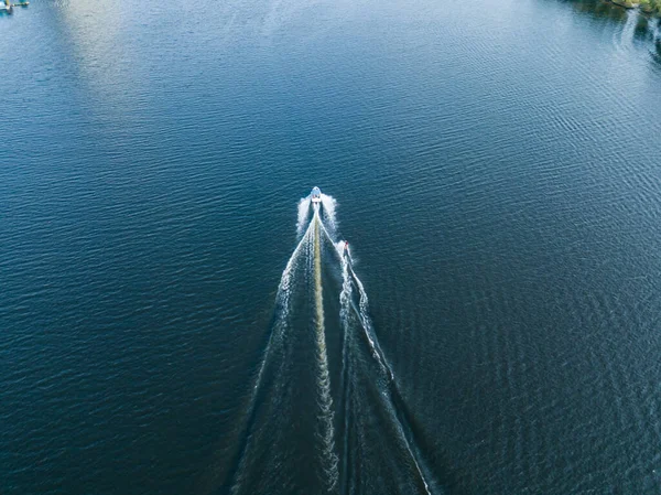 Aerial drone view. Wake surfing behind a boat on the river on a sunny summer day.
