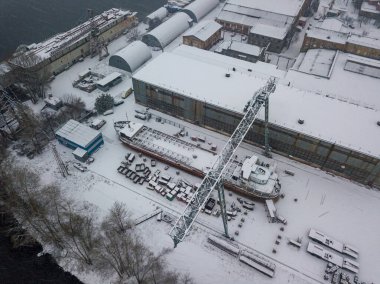 Karla kaplı bir tersanede bir vinç. Kar fırtınası, kar fırtınası. Hava aracı görünümü.