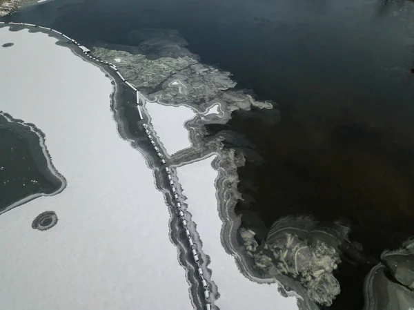 Aerial drone top view. Frosty pattern drawing on the river. Cloudy frosty winter morning.