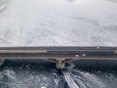 Hava aracı görüntüsü. Kiev 'deki metro köprüsü nehirdeki buz tabakalarının arasında. Bulutlu, dondurucu kış sabahı.