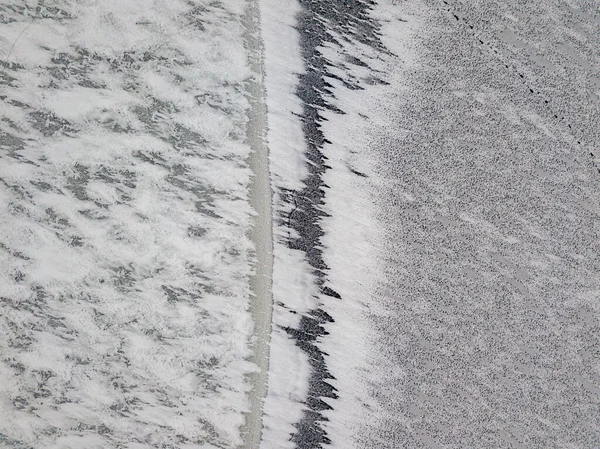 Aerial drone top view. Frosty pattern drawing on the river. Cloudy frosty winter morning.