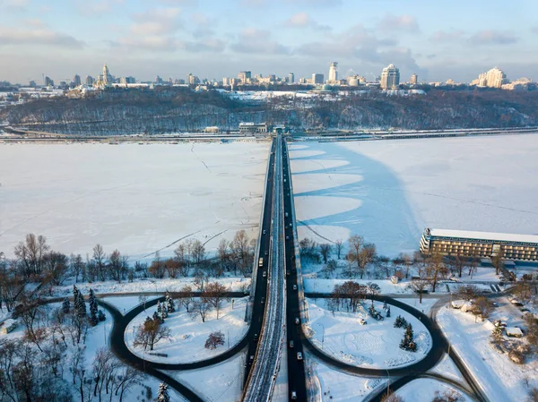 Aerial drone view. The shadow from the metro bridge in Kiev falls on the frozen Dnieper River. Sunny winter morning.