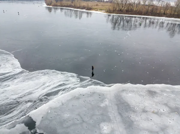 Fisherman on thin ice. Frosty drawing on ice. Aerial drone view. Winter cloudy morning.