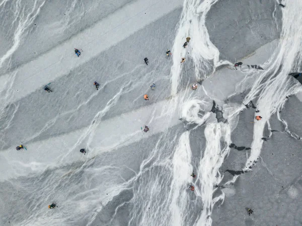 Fishermen on thin ice. Frosty drawing on ice. Aerial drone view. Winter cloudy morning.