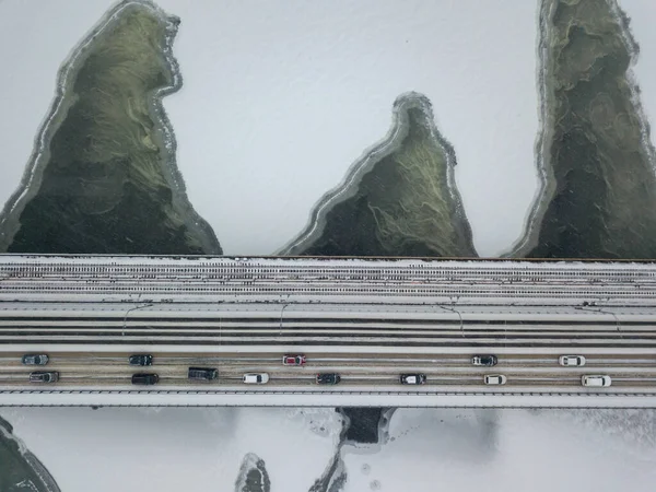 Kiev metro bridge over the frozen Dnieper river. Texture drawing on ice. Aerial drone view. Winter snowy morning.