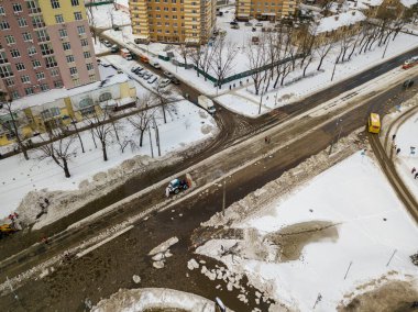 Traktör yoldaki suyu temizliyor. Hava aracı görüntüsü. Kış karlı sabah.