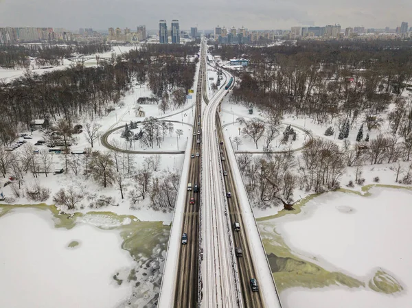 Kiev metro bridge over the frozen Dnieper river. Texture drawing on ice. Aerial drone view. Winter snowy morning.