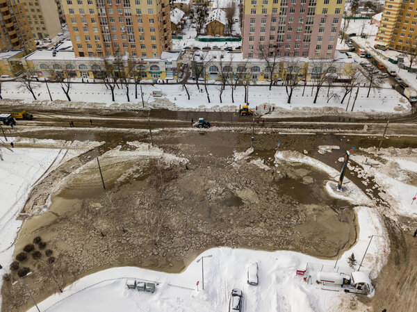 Pipeline failure in the city. Aerial drone view. Winter snowy morning.