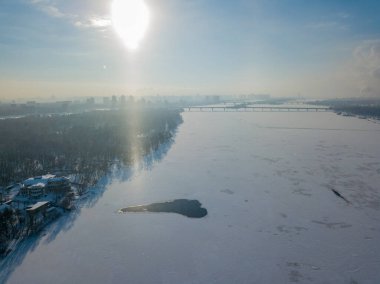 Kiev 'deki Dinyeper nehrinin üzerindeki güneşten gelen ışık sütunu. Hava aracı görüntüsü. Kış güneşli sabah.