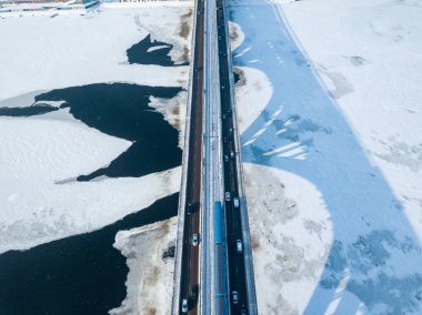 Bir metro treni Kiev metro köprüsü boyunca seyahat eder. Donmuş Dinyeper Nehri 'ne bir gölge düşüyor. Hava aracı görüntüsü. Kış güneşli sabah.