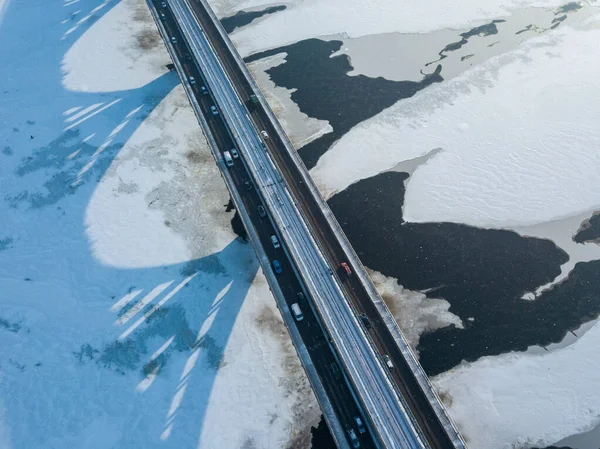 Kyiv metro bridge. A shadow falls on the frozen Dnipro river. Aerial drone view. Winter sunny morning.