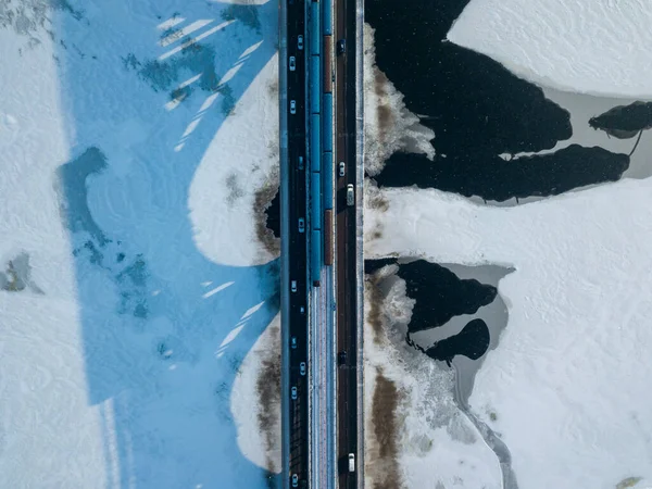 Two metro trains travel on Kiev metro bridge. A shadow falls on the frozen Dnieper River. Aerial drone view. Winter sunny morning.