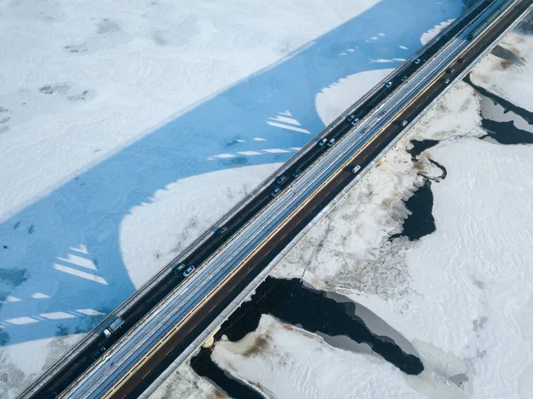 Kyiv metro bridge. A shadow falls on the frozen Dnipro river. Aerial drone view. Winter sunny morning.