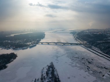 Kiev 'deki donmuş Dinyeper nehri. Hava aracı görüntüsü. Kış dondurucu bir sabah. Güneş bulutların arasından doğar.