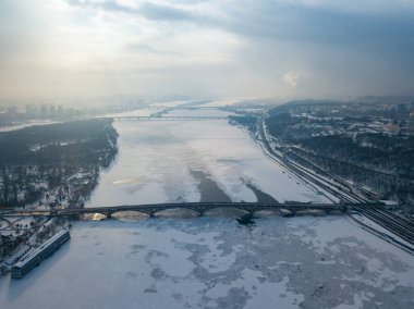 Kiev 'deki donmuş Dinyeper nehri. Hava aracı görüntüsü. Kış dondurucu bir sabah. Güneş bulutların arasından doğar.