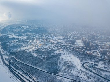 Snow-covered Kiev-Pechersk Lavra in a blizzard. Aerial drone view. Snowy winter morning, blizzard. Black cloud over the city.