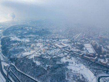 Snow-covered Kiev-Pechersk Lavra in a blizzard. Aerial drone view. Snowy winter morning, blizzard. Black cloud over the city.