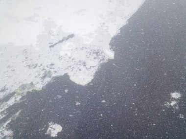 Ice edge on the river in a blizzard. Aerial drone view. Snowy winter morning, blizzard.