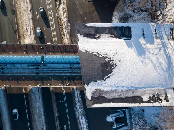 Kiev metro train at a stop on the bridge. Aerial drone view. Winter sunny morning.