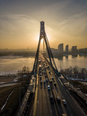 Günbatımında Kiev 'de Kuzey Köprüsü. Hava aracı görüntüsü. Bahar akşamı, güneş ışınları köprünün sütunlarından geçer..