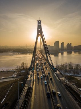 Günbatımında Kiev 'de Kuzey Köprüsü. Hava aracı görüntüsü. Bahar akşamı, güneş ışınları köprünün sütunlarından geçer..