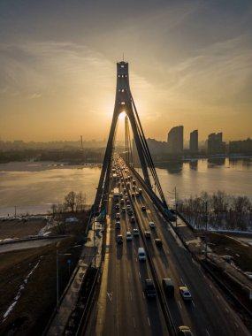 Günbatımında Kiev 'de Kuzey Köprüsü. Hava aracı görüntüsü. Bahar akşamı, güneş ışınları köprünün sütunlarından geçer..