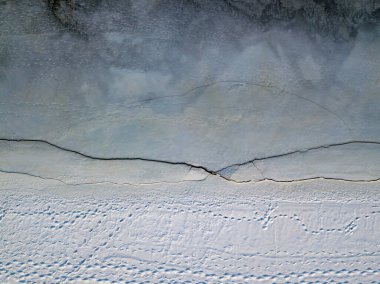 Nehir kıyısı eriyor. Nehirdeki buz çatlağı. Hava aracı görüntüsü. Bahar güneşli sabah.