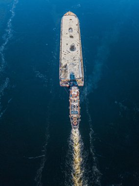 Mavna dondurucu nehirde yüzüyor. Hava aracı görüntüsü. Güneşli kış günü, nehirde ince buz.