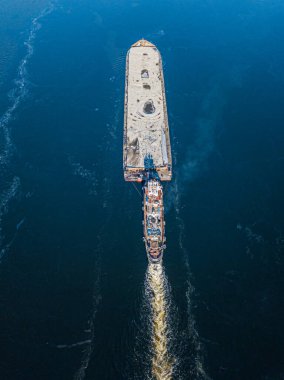 Mavna dondurucu nehirde yüzüyor. Hava aracı görüntüsü. Güneşli kış günü, nehirde ince buz.