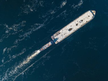 Mavna dondurucu nehirde yüzüyor. Hava aracı görüntüsü. Güneşli kış günü, nehirde ince buz.