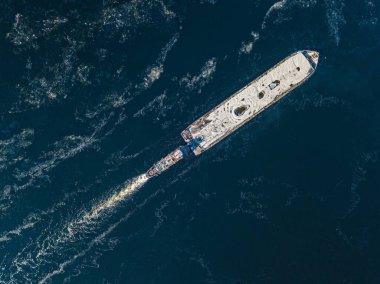 Mavna dondurucu nehirde yüzüyor. Hava aracı görüntüsü. Güneşli kış günü, nehirde ince buz.