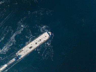 Mavna dondurucu nehirde yüzüyor. Hava aracı görüntüsü. Güneşli kış günü, nehirde ince buz.