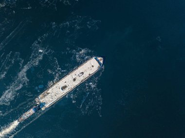 Mavna dondurucu nehirde yüzüyor. Hava aracı görüntüsü. Güneşli kış günü, nehirde ince buz.