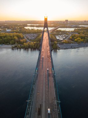Kiev 'in kuzey köprüsü. Köprü boyunca yükselen güneş ışınları. Güneş pilonun içinden doğuyor. Hava aracı görünümü.
