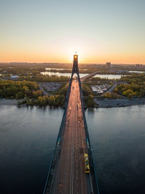Kiev 'in kuzey köprüsü. Köprü boyunca yükselen güneş ışınları. Güneş pilonun içinden doğuyor. Hava aracı görünümü.