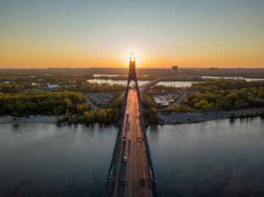 Kiev 'in kuzey köprüsü. Köprü boyunca yükselen güneş ışınları. Güneş pilonun içinden doğuyor. Hava aracı görünümü.