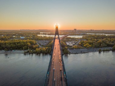 Kiev 'in kuzey köprüsü. Köprü boyunca yükselen güneş ışınları. Güneş pilonun içinden doğuyor. Hava aracı görünümü.