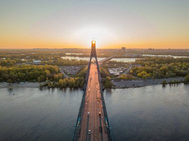 Kiev 'in kuzey köprüsü. Köprü boyunca yükselen güneş ışınları. Güneş pilonun içinden doğuyor. Hava aracı görünümü.