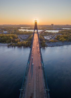 Kiev 'in kuzey köprüsü. Köprü boyunca yükselen güneş ışınları. Güneş pilonun içinden doğuyor. Hava aracı görünümü.
