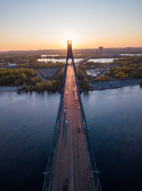 Kiev 'in kuzey köprüsü. Köprü boyunca yükselen güneş ışınları. Güneş pilonun içinden doğuyor. Hava aracı görünümü.