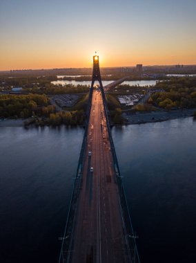 Kiev 'in kuzey köprüsü. Köprü boyunca yükselen güneş ışınları. Güneş pilonun içinden doğuyor. Hava aracı görünümü.