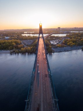 Kiev 'in kuzey köprüsü. Köprü boyunca yükselen güneş ışınları. Güneş pilonun içinden doğuyor. Hava aracı görünümü.