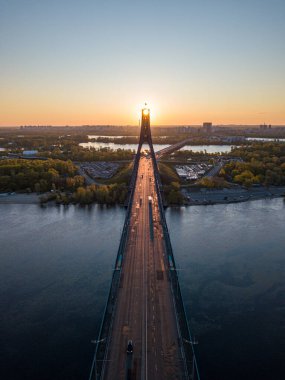 Kiev 'in kuzey köprüsü. Köprü boyunca yükselen güneş ışınları. Güneş pilonun içinden doğuyor. Hava aracı görünümü.