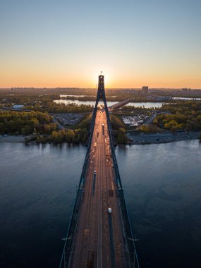 Kiev 'in kuzey köprüsü. Köprü boyunca yükselen güneş ışınları. Güneş pilonun içinden doğuyor. Hava aracı görünümü.